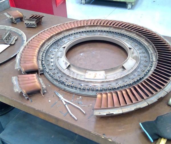 metal components of a gas turbine engine on a workbench with tools nearby showcasing precision engineering