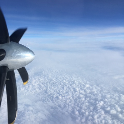 aircraft propeller with clouds below and blue sky above