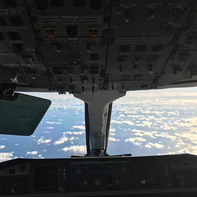 inside airplane cockpit with control panel and clouds visible outside offering a view of aviation and flight management